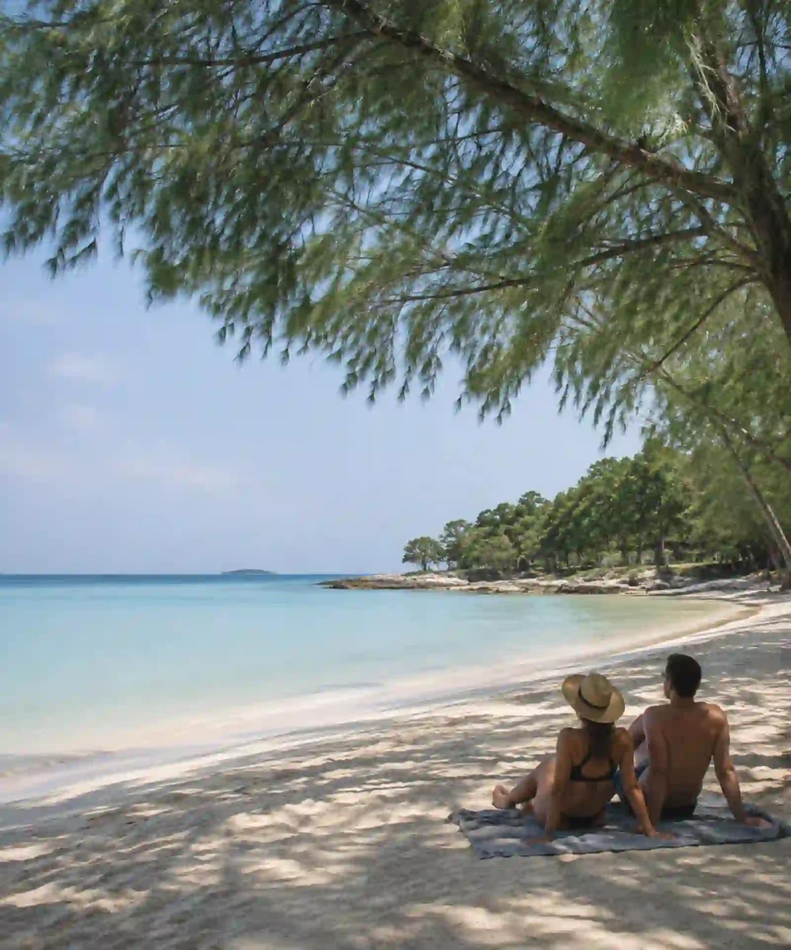 Koh Samet Sun, Sand, and Samet: What You Need to Know Before You Go 3 A couple relaxing beneath trees beside a calm Koh Samet beach in clear weather